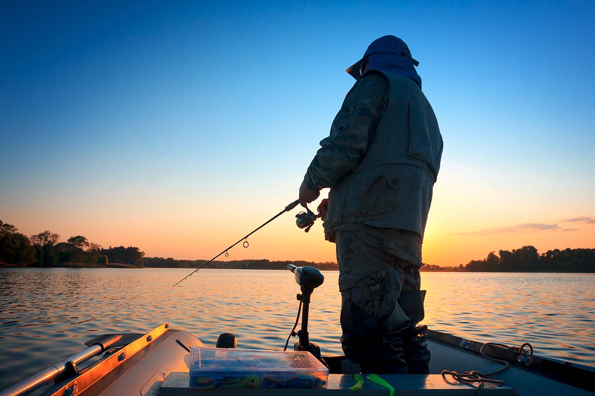 A fisherman fishing in a lake at sunset